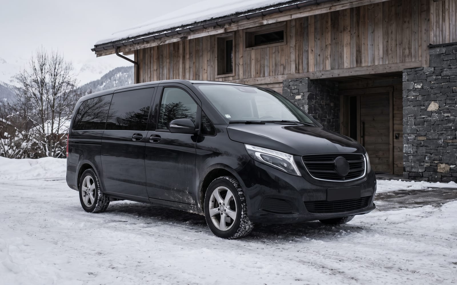 Black Mercedes V-Class on packed snow outside a contemporary alpine building